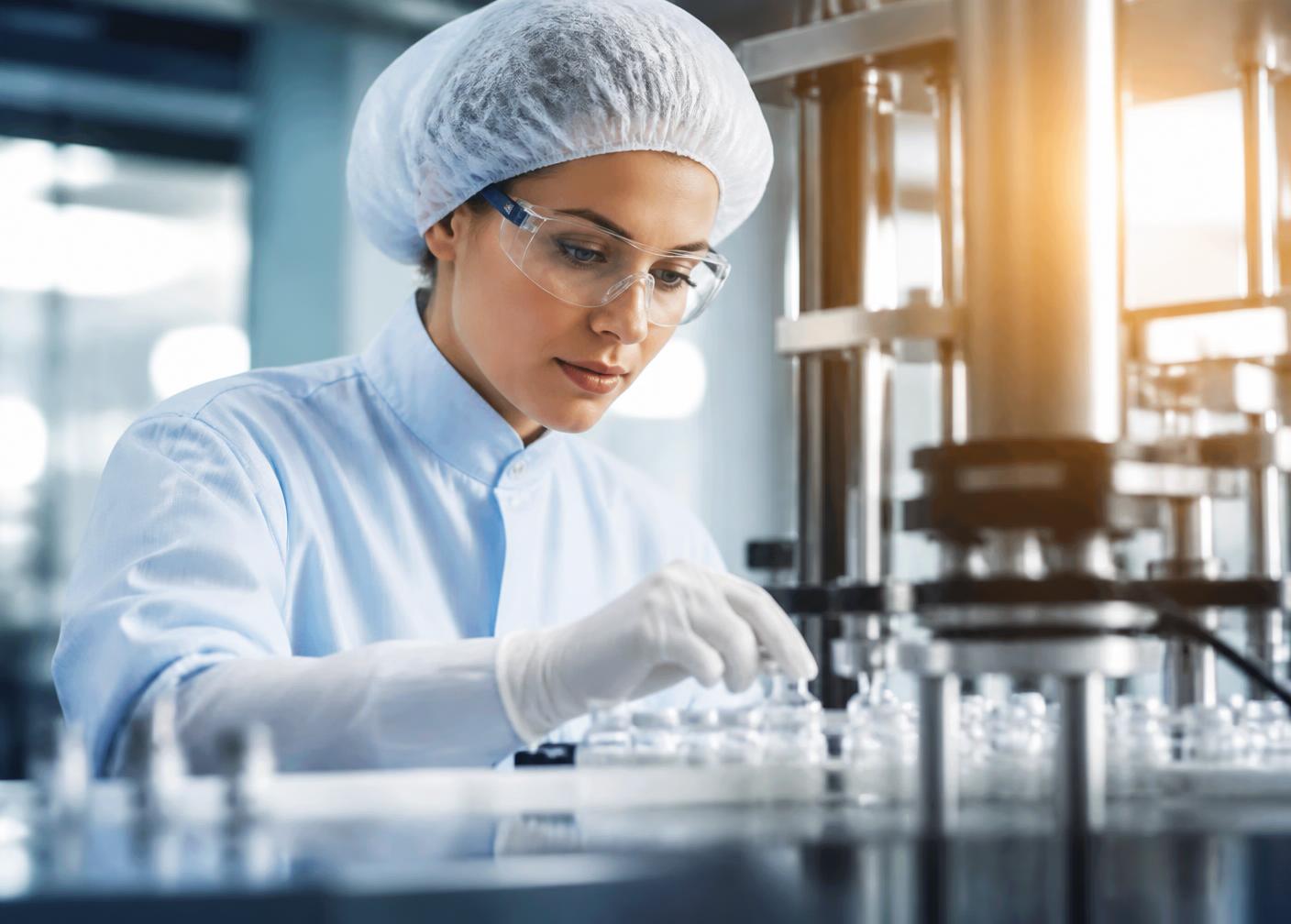 Farmacêutica em sala limpa acompanhando o envase asséptico